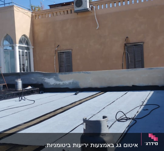 גג עם יריעות איטום, בלוני גז וצינורות.